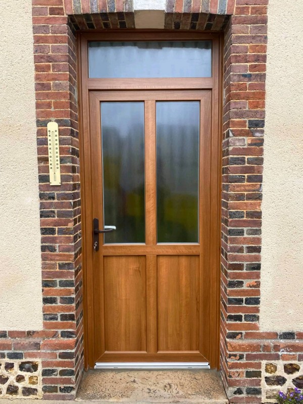 Porte d'entrée PVC Blanc teinté masse intérieure et plaxé chêne mat extérieur posé au alentour de la Barre en Ouche (27) par Leroy Fermetures